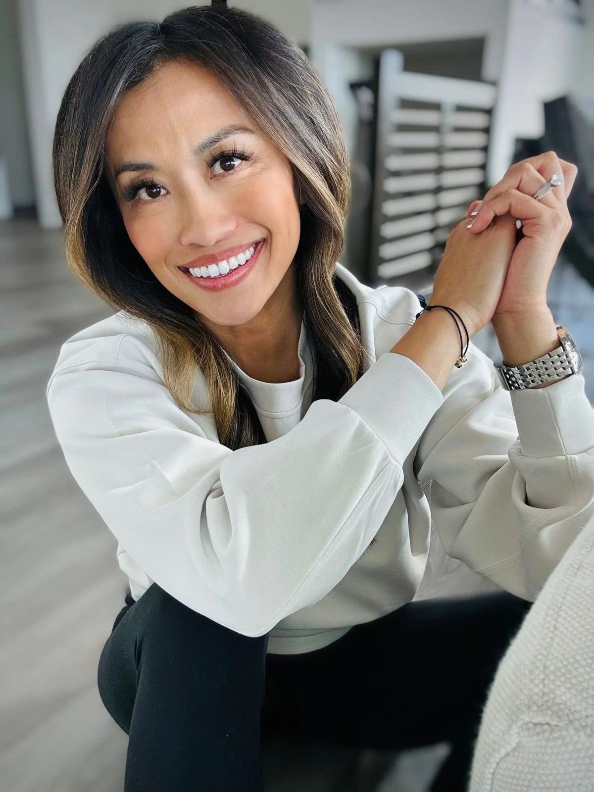 Suttida smiling, hands clasped, in a white sweatshirt