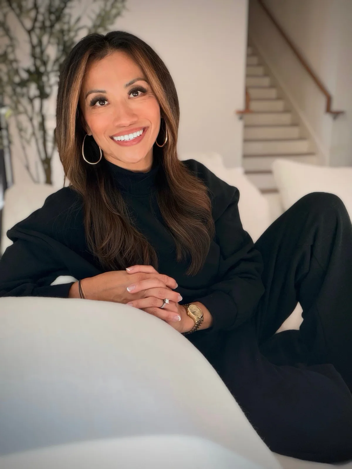 Suttida smiling on a white sofa, in a black outfit